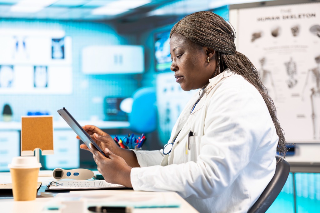 Praticienne consultant le dossier patient et imagerie médicale sur tablette